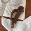 Primer plano de una pinza para el pelo en forma de corazón marrón en un libro, detalle estético. - 12.5cm / Marrón Transparente