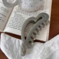 Primer plano detallado de una pinza para el pelo con forma de corazón gris sobre un libro. - 12.5cm / Gris Cemento