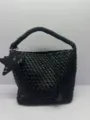 Detailed view of the stylish black woven leather bucket bag featuring unique star charms. - Black