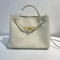 Elegant beige leather bucket bag featuring braided handles and chic gold bow hardware for women. - Off White