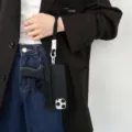 Creatief pistolvorm telefoonhoesje detailfoto, cool zwart ontwerp met handige koord. - Zwart lederen textuur + speelgoedpistool + polsbandje / iPhone 16 Pro met groot gat