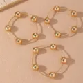 Detalle en primer plano del set de pulseras doradas con cuentas pulidas y cadenas finas. - Estilo 7