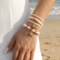 Λεπτομερές κοντινό πλάνο σετ boho βραχιολιών με κοχύλια και λευκές πέρλες σε παραλία. - Πολυστρωματικό Στυλ Αστερίας Κοχύλι Μαργαριτάρι / Λευκό (BS0014)