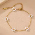 Nahaufnahme Detail des goldenen Armbands mit weißen Perlenblumen Anhängern und Karabiner. - Einzeln / Weiß
