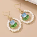 Primer plano de elegantes pendientes de perlas con flor de vidrio azul y ganchos. - Estilo Tulipán Azul / Azul