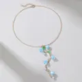 Dettagliata ripresa ravvicinata della collana con catena dorata, fiori blu e perle pendenti. - Stile Blu (NZ2970)