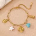 Detailaufnahme eines Boho-Meeres-Charm-Armbands mit Fisch-, Seestern- und Türkis-Anhängern. - Einzeln Fisch / Gold