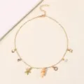 Nahaufnahme Detail der goldenen Meeres-Charm-Halskette mit Seestern- und Muschelanhängern. - Buchstabe O Stil (NZ3241-O) / Gold