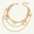 Close-up detail of the multi-layer gold-plated butterfly and heart charm anklet design. - Gold
