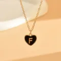 Detailaufnahme der goldenen Kette mit einem schwarzen Herzanhänger und dem Buchstaben F. - Buchstabe F (NZ2864) / Schwarz