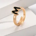 Nahaufnahme eines stilvollen vergoldeten offenen Rings mit schwarzem Buchstaben M Akzent. - Buchstabe M / Gold