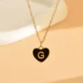 Nahaufnahme Detail der filigranen Goldkette mit schwarzem Emaile-Herz-Anhänger und Buchstabe G. - Buchstabe G (NZ2864) / Schwarz