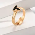 Detailaufnahme des goldenen verstellbaren offenen Damenrings mit eleganten schwarzen Buchstaben T. - Buchstabe T / Gold