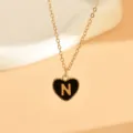 Nahaufnahme einer Goldkette mit einem schwarzen Emaille-Herz-Anhänger und der Letter N. - Buchstabe N (NZ2864) / Schwarz