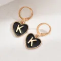 Detailansicht der goldenen Creolen mit schwarzem Herzanhänger und dem goldenen Buchstaben K. - Herz Buchstabe K Stil