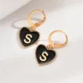 Goldene Creolen mit schwarzem Herz-Anhänger und Buchstabe S, elegante französische Detailansicht. - Herz Buchstabe S Stil