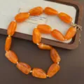 Leuchtend orangefarbene Perlenkette aus Harz mit goldenem Verschluss, stilvolles Accessoire. - Orange