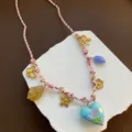 Nahaufnahme der süßen geflochtenen Charm-Halskette mit floralen und Herz-Anhängerdetails. - Herz Schmetterling Blumen Stil / Rosa