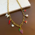 Close-up detail view of the gold chain necklace with colorful fruit charms and pearl pendants. - Grape Necklace (05-E23) / Gold