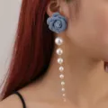 Nahaufnahme eines stylischen blauen Jeansrosen-Ohrrings kombiniert mit einer langen Perlenquaste. - Beflockter Rosen-Stil / Blau