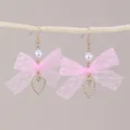 Nahaufnahme von rosa Spitzen Schleife Ohrringen mit weißer Perle und Herz Anhänger Detail. - Rosa (EZ5585)
