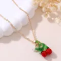 Gold chain necklace featuring a cute red resin cherry pendant and delicate flower detail. - Cherry
