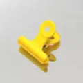Primer plano de un clip de metal amarillo brillante con agujero para colgar oficina y escuela. - Amarillo Limón