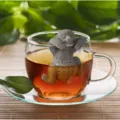 Cute sloth shaped silicone tea infuser hanging on a glass cup of hot tea - Koala