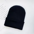 Close-up detail of a solid black knitted beanie hat, showcasing winter warm soft wool texture. - One Size / Black