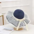 Detailed view of the elegant navy blue straw sun hat with delicate white mesh trim and lace bow. - Navy Blue