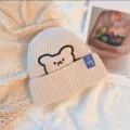 Beanie hat for women with cute bear embroidery, warm knitted winter cap with tag. - One Size / Beige