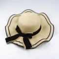 Stylish women's summer straw hat with a black bowknot and elegant wavy brim design. - Beige