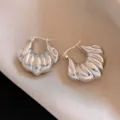 Vue détaillée de boucles d'oreilles créoles argentées épaisses et nervurées, style élégant. - Argent