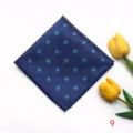 Detail view of a navy blue pocket square featuring delicate light blue floral jacquard pattern. - Style 9