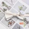 Detail view of a chic beige satin double layer bow tie with white flower and rhinestone accent. - Arrow Shape / Off White