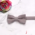 Close-up detail of a soft solid color children bow tie on marble background with rose. - Style J