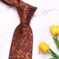 Detailed view of men's floral woven necktie in dark red with golden floral pattern. - Style J