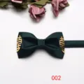 Primer plano de la pajarita de boda verde oscuro con elegantes detalles metálicos dorados. - Verde oscuro