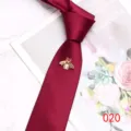 Detail view of a burgundy men's necktie featuring an elegant gold pearl bee brooch decoration. - Color 020