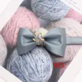 Dettaglio di farfalla in raso grigio con elegante accessorio in metallo dorato a foglia. - Grigio