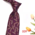 Detail view of burgundy men's necktie featuring elegant gold feather jacquard pattern design. - Dark Purple Red
