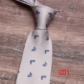 Detail shot of a grey necktie featuring a cute blue jumping rabbit pattern print close-up. - 001