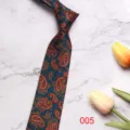 Detailed close-up of a dark teal paisley patterned men's tie with elegant floral design. - 7CM005