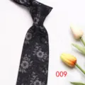Close-up detail of a stylish black necktie featuring intricate grey floral patterns. - Color 009