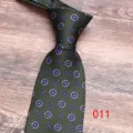 Close-up detail of a dark green silk tie featuring elegant medallion floral print patterns. - 011