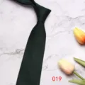 Detailed view of dark green herringbone silk tie, elegant business style with floral prop background. - 8CM019
