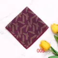Detail shot of a men's polyester pocket square featuring a stylish gold feather pattern on a deep red fabric. - Color 005