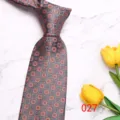Close-up detail of grey men's patterned necktie featuring classic small floral geometric design. - Gray Orange Print (027)