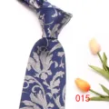 Close-up detail of a classic blue men's necktie featuring an intricate silver floral jacquard pattern. - 015 (Blue Floral)