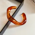 Close-up detail of the irregular geometric amber acrylic open bangle showing glossy texture. - Bangle-Amber